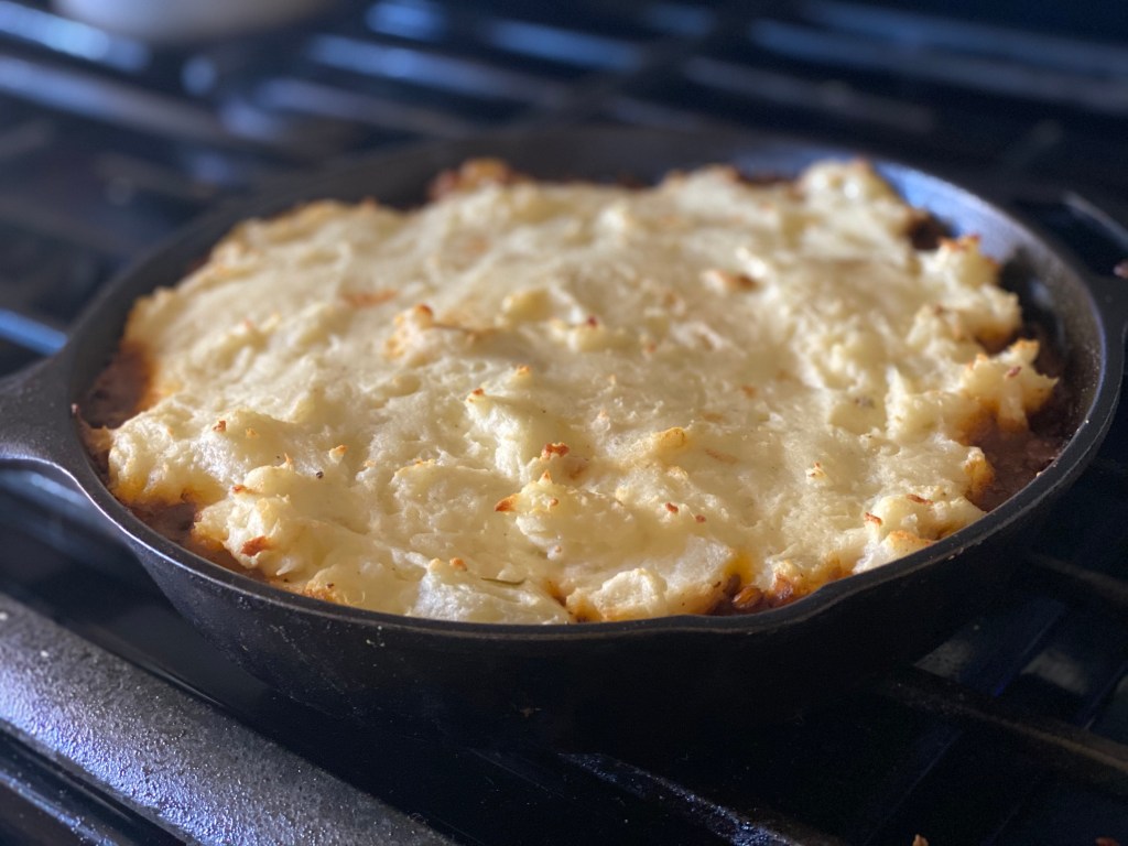 Lentil Shepherd's Pie in a cast iron pan over a stove.